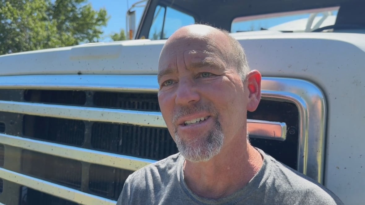 Man stands in front of truck and smiles