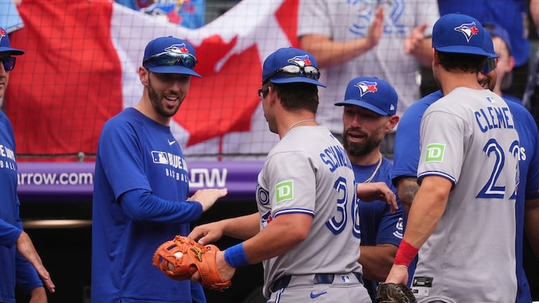 Men's baseball players greet each other entering a dugout.