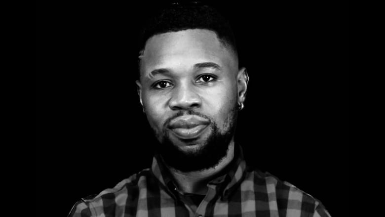 A man wearing a checked shirt is seen in a black-and-white headshot.