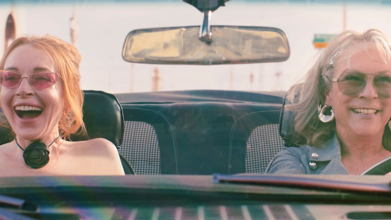 Two smiling women in a car are shown.