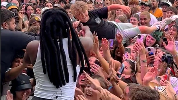 Tristan Kaulbach crowd surfed his way to meet Shaboozey at Osheaga in Montreal. A teen with a big smile crowd surfing