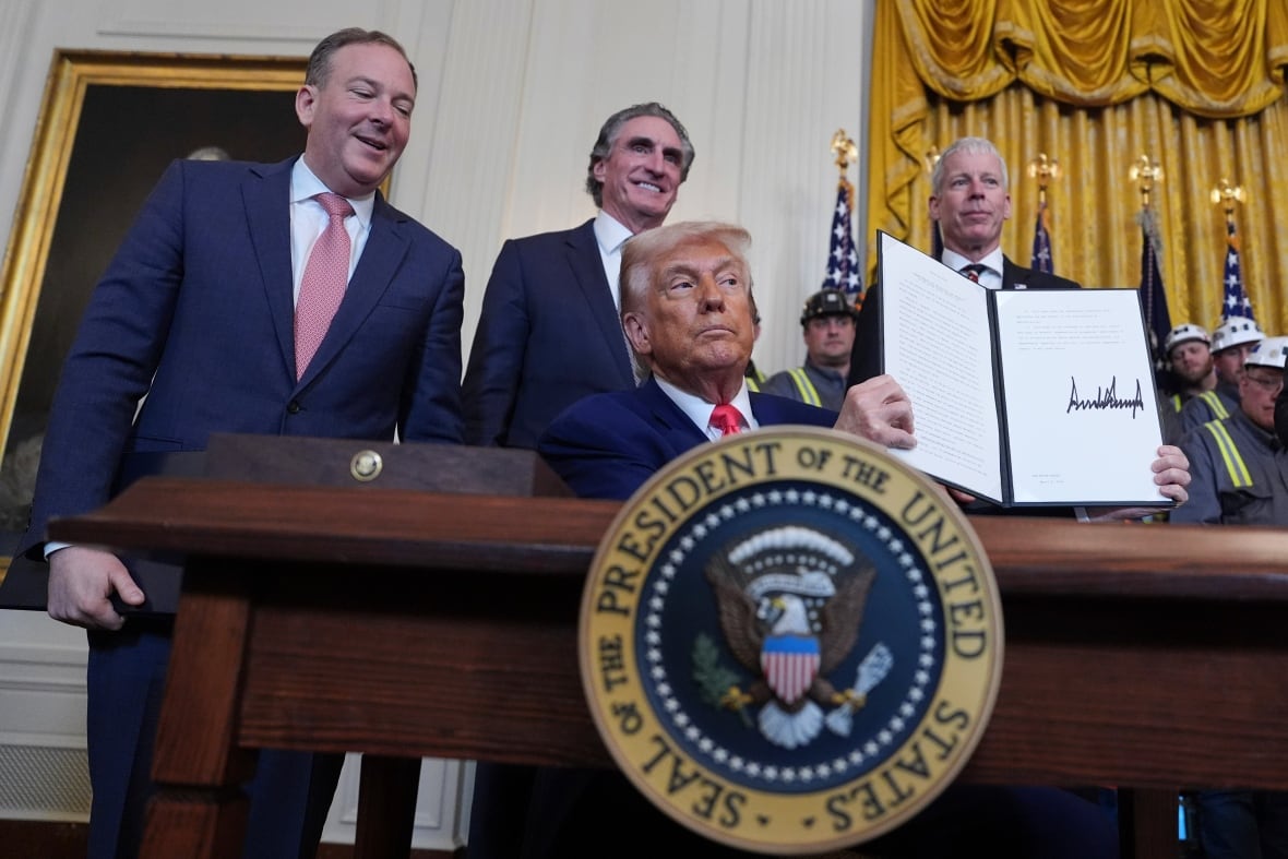 President Donald Trump holds up a signed sheet of paper