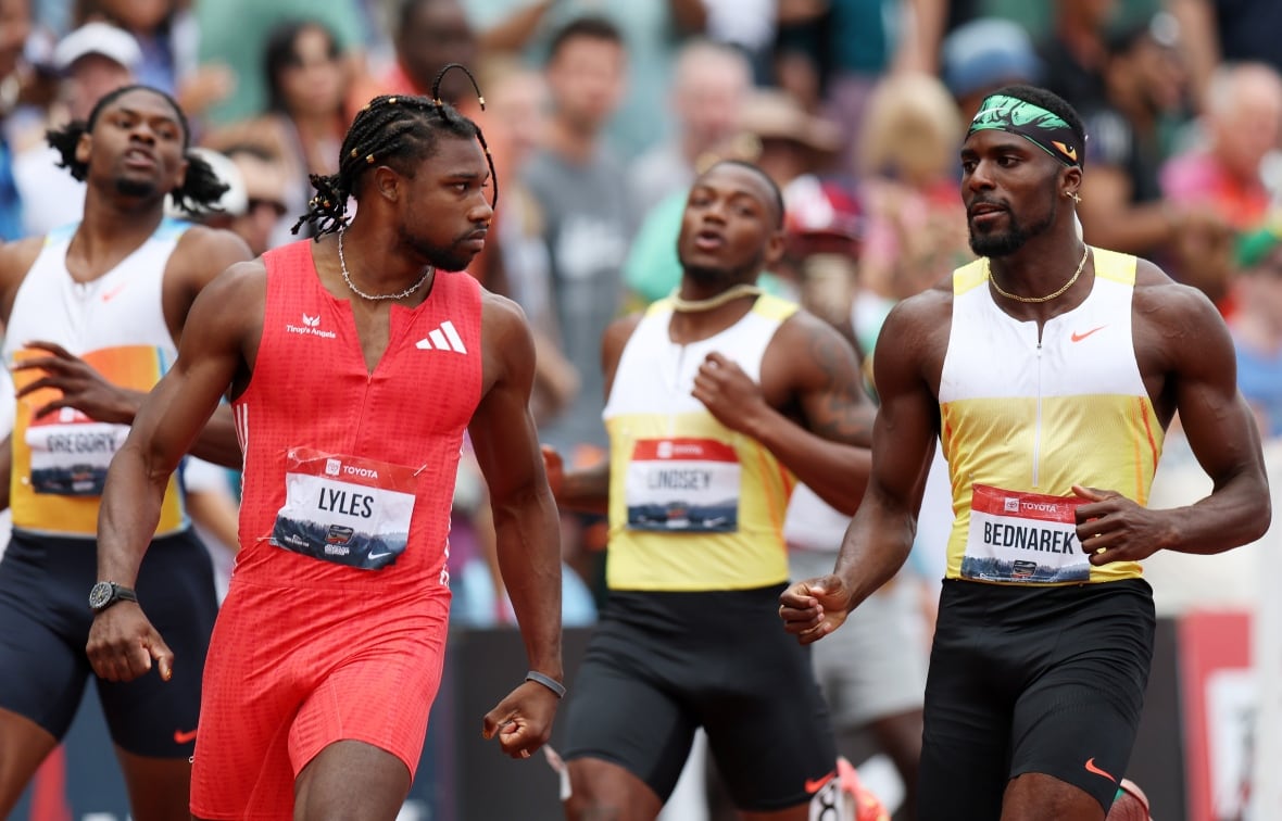 A runner stares down another runner at the finish line.