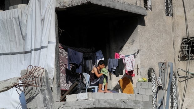 A person sits inside a partially collapsed building.