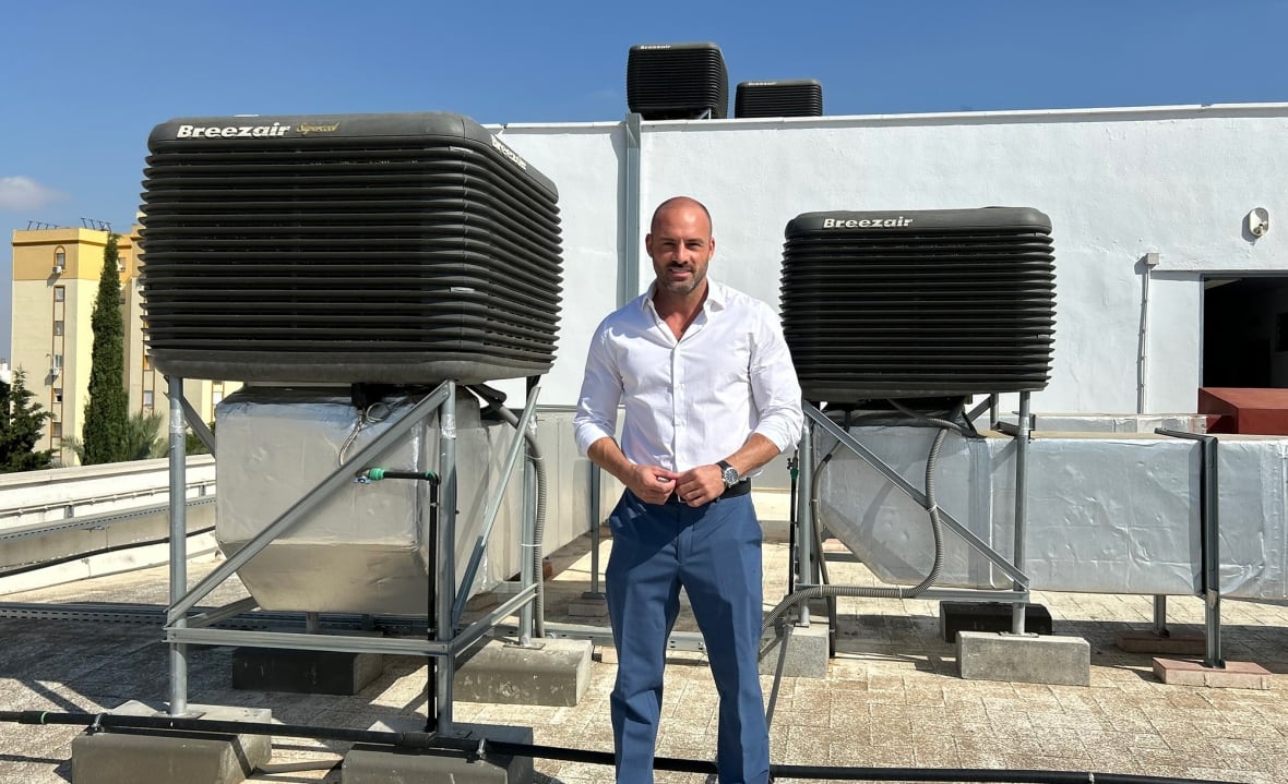 A man stands next to machines installed on the roof of a school in Seville.