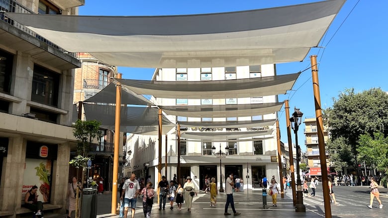 Street shades stretched between buildings protect pedestrians from the sun.