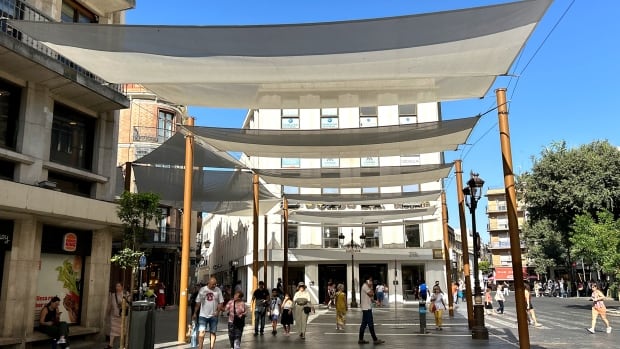 Street shades stretched between buildings protect pedestrians from the sun.