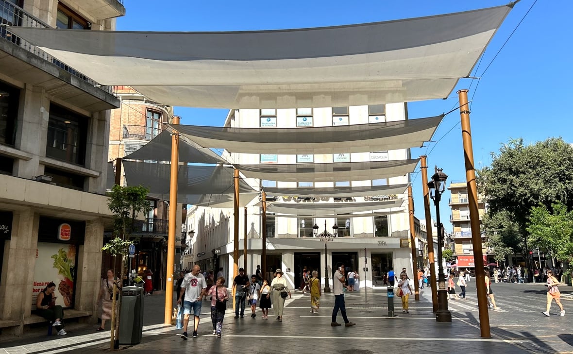 Street shades stretched between buildings protect pedestrians from the sun.