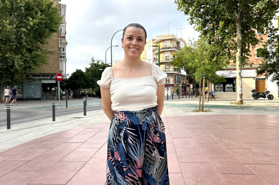 A woman stands on a street corner in Spain.