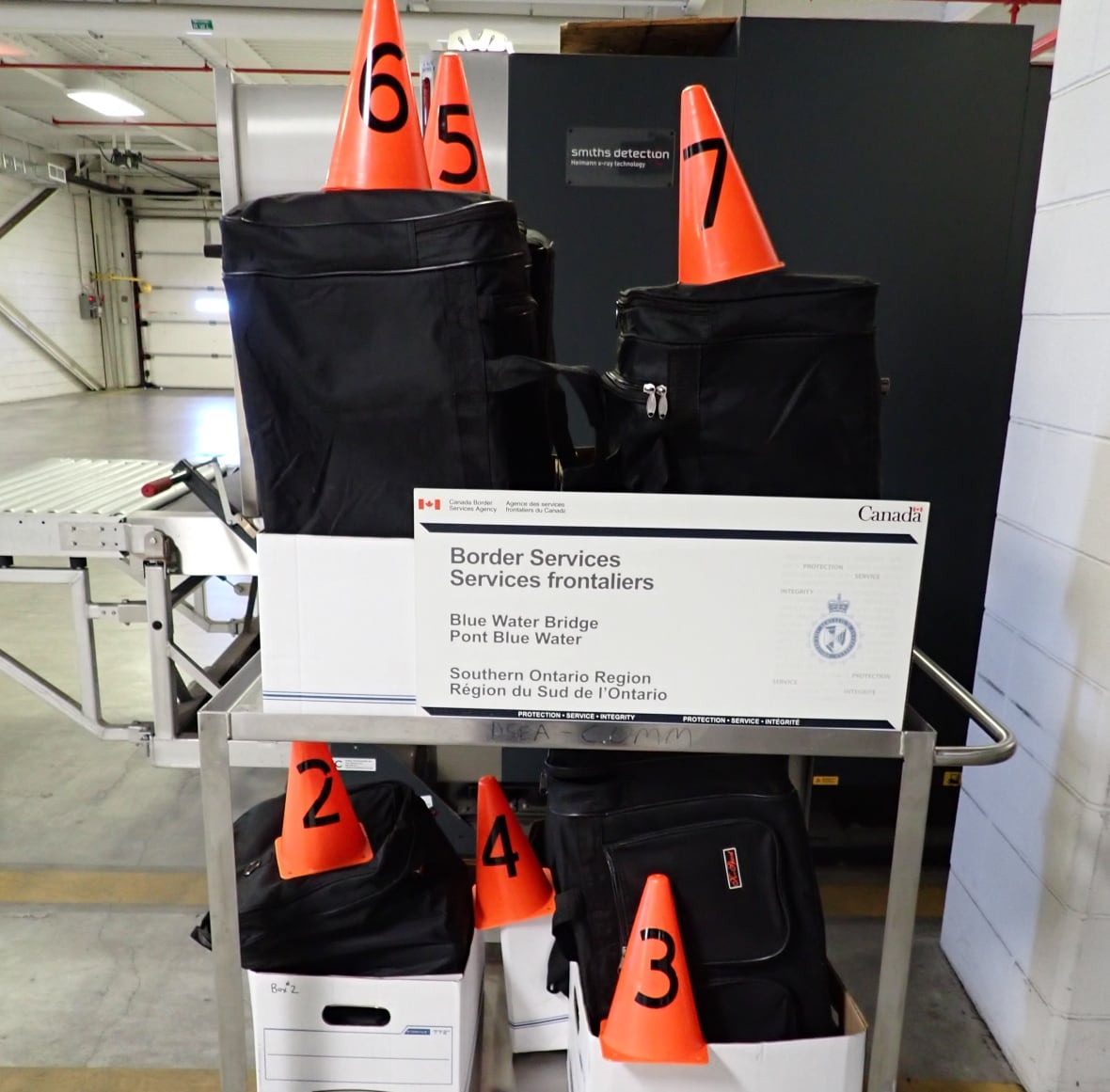 black duffle bags in white boxes with orange pylons on top