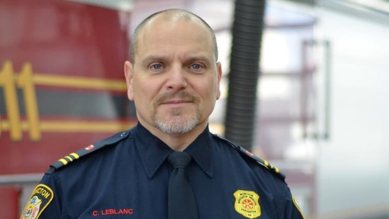A man in a fire department uniform, smiling.