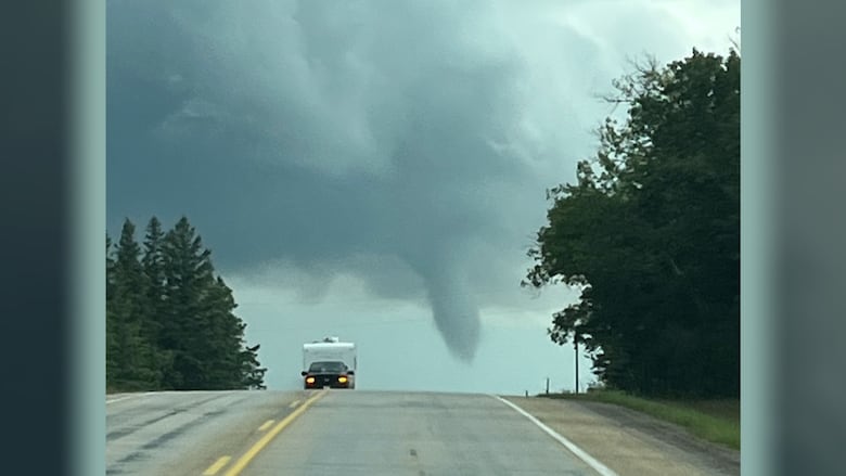 A funnel cloud is seen in the distance.