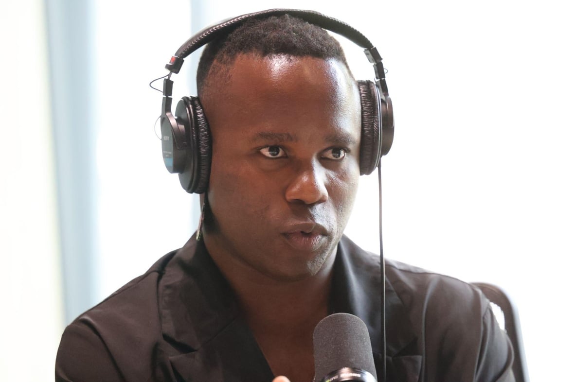 A man with headphones on sitting behind a microphone. 