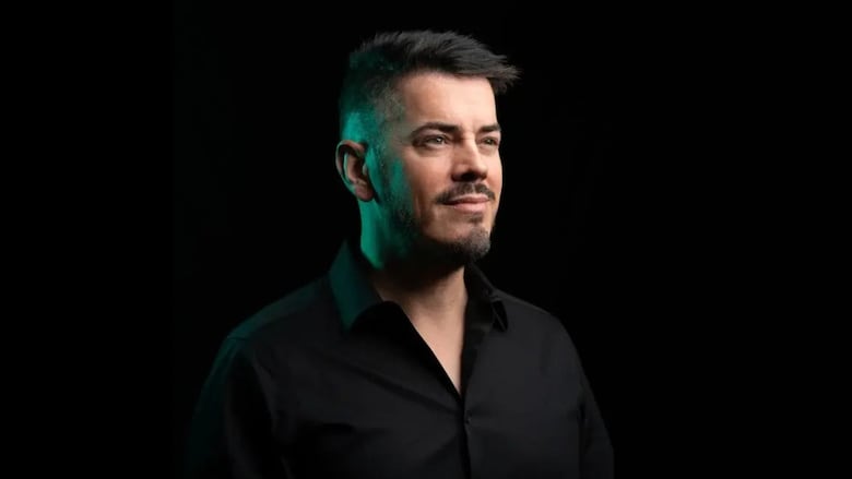A man wearing a black shirt and a black background. 