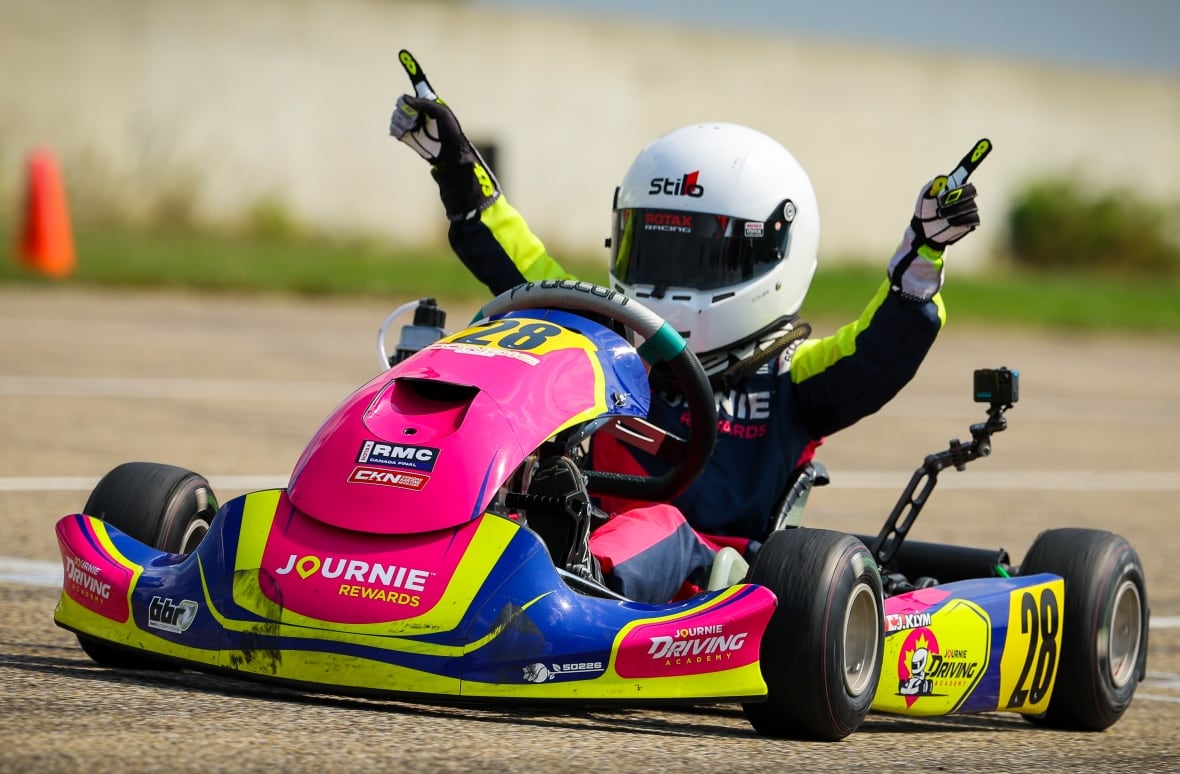 Klym rides in a go-kart holding up his first finger, signifying that he's number one.