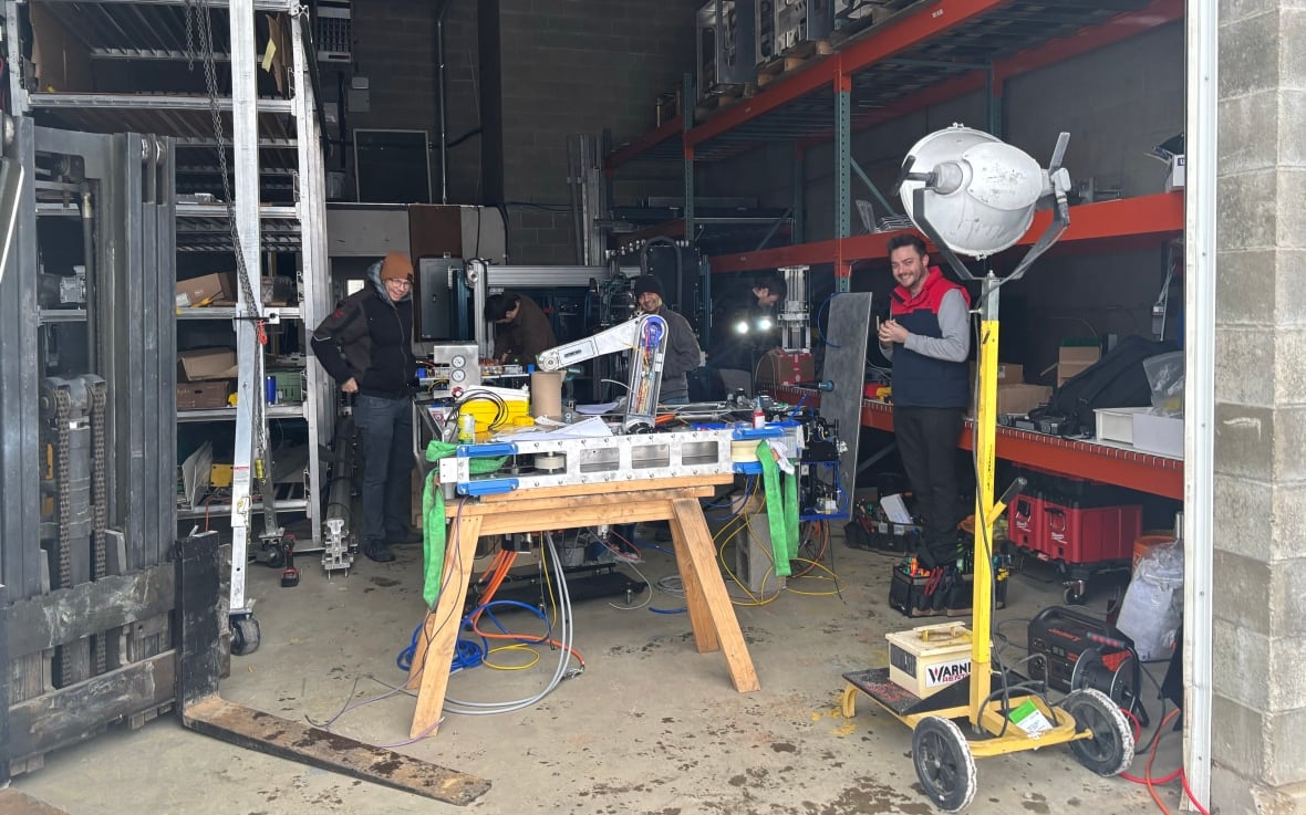 Un garage industriale con cinque uomini al suo interno che lavorano su un macchinario.