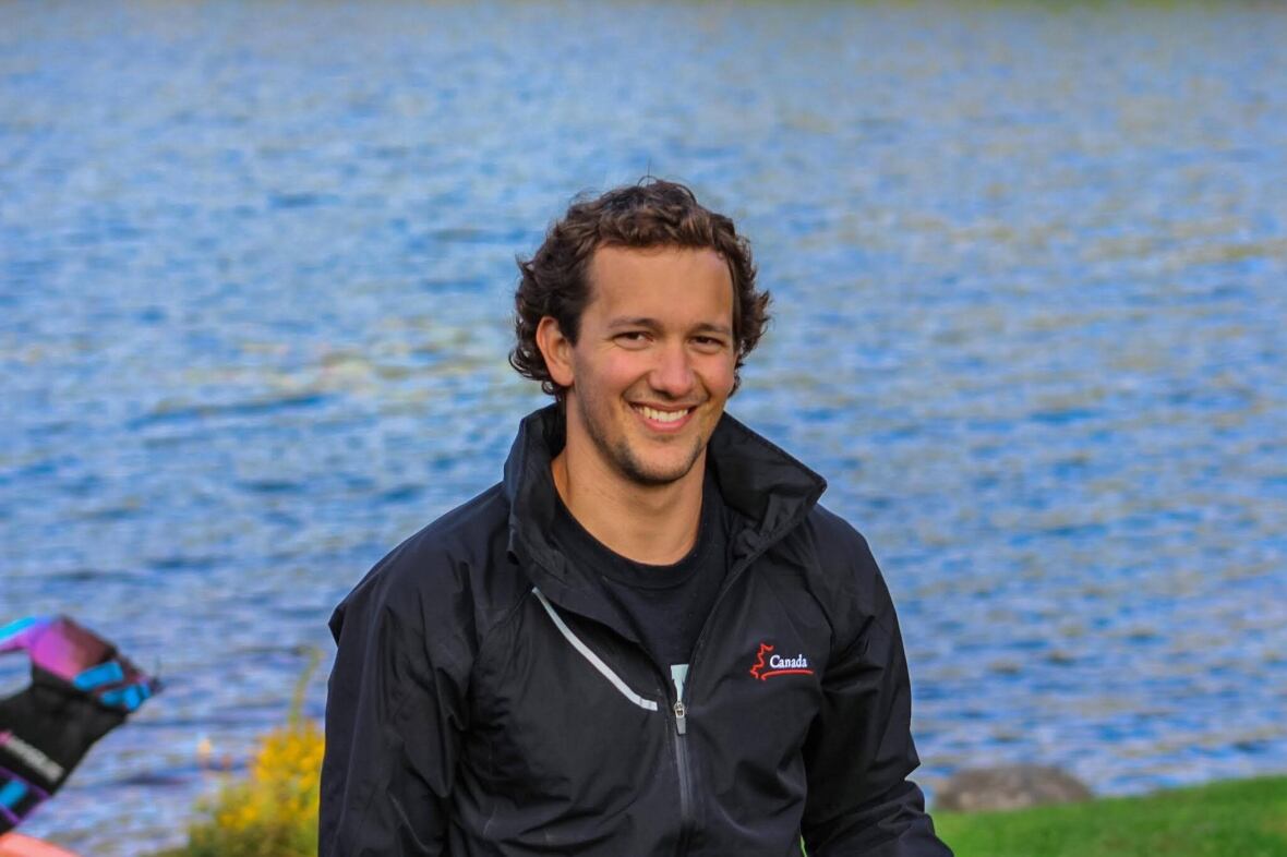 A man smiles in front of open water