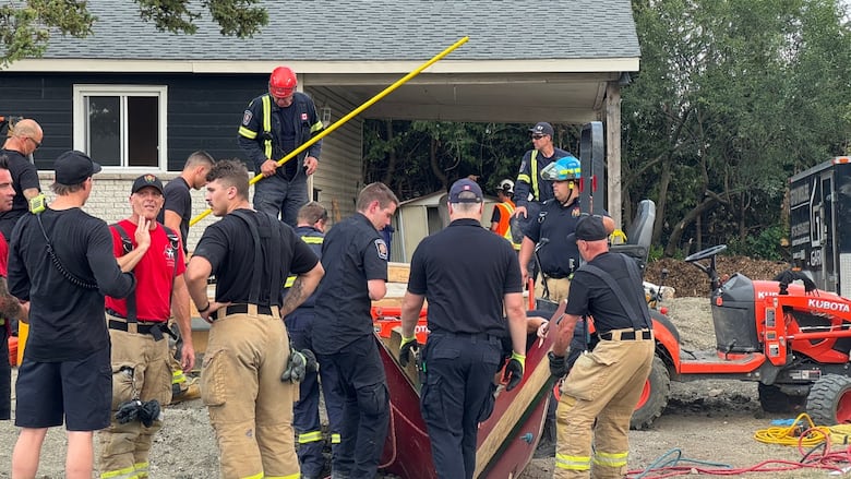 Several first responders rescue a man at a worksite on a summer day.