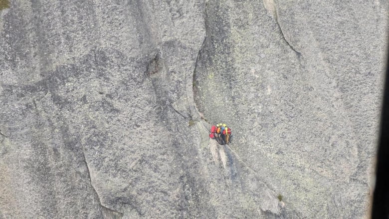 Two climbers and rescue technicians seen clinging to a narrow ledge on the sheer face of Yak Peak near Hope, B.C. on Wednesday.