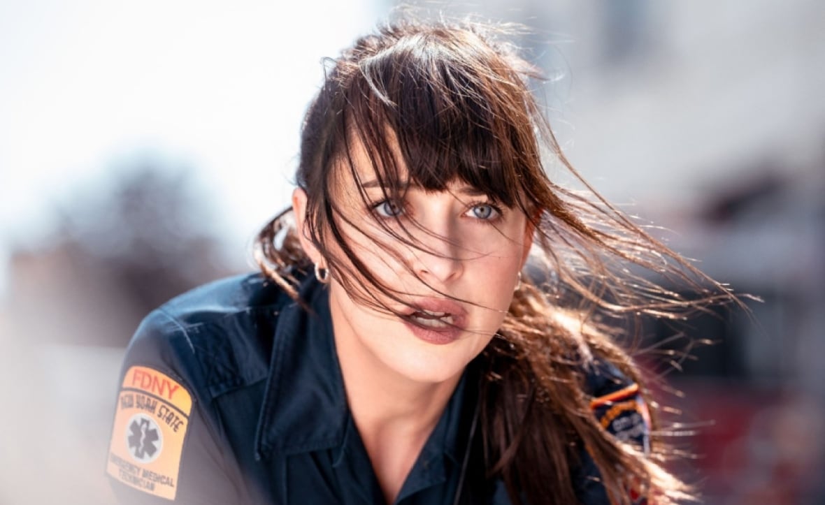 Primo piano di una donna in uniforme da paramedico che guarda fuori dallo schermo.