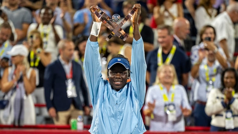 A young woman holds up a trophy above her head.