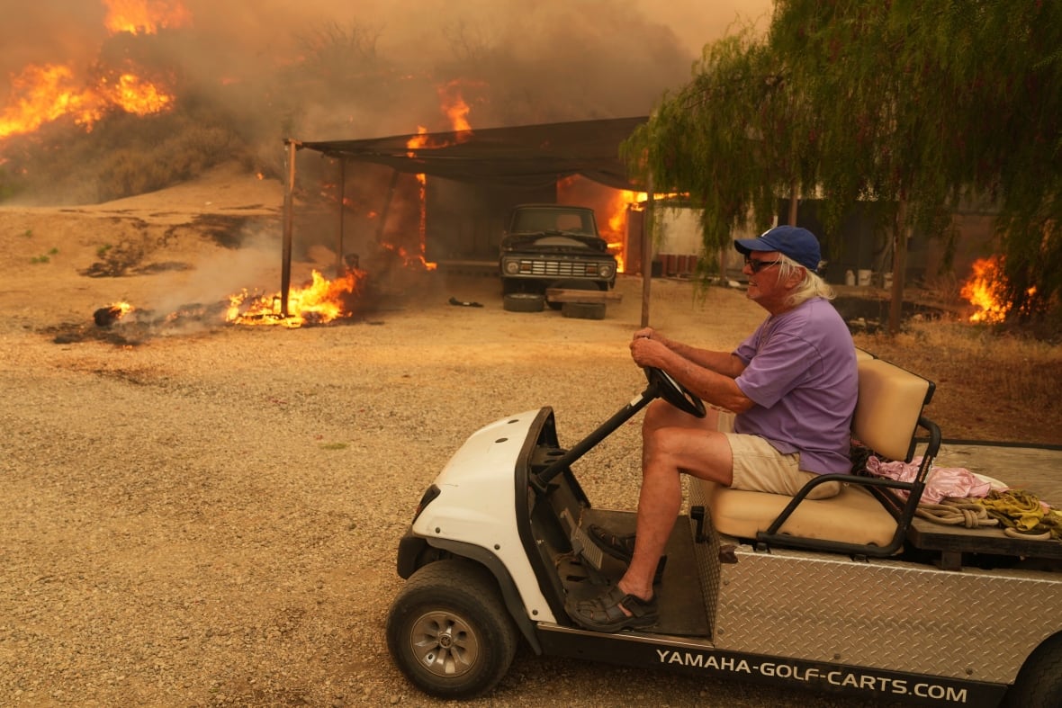One of the residents rides a golf vehicle while leaving his possessions amid a burning burning in Halsusi Canyon, California.
