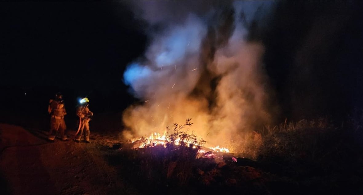 Two firefighters fighting fire late at night.