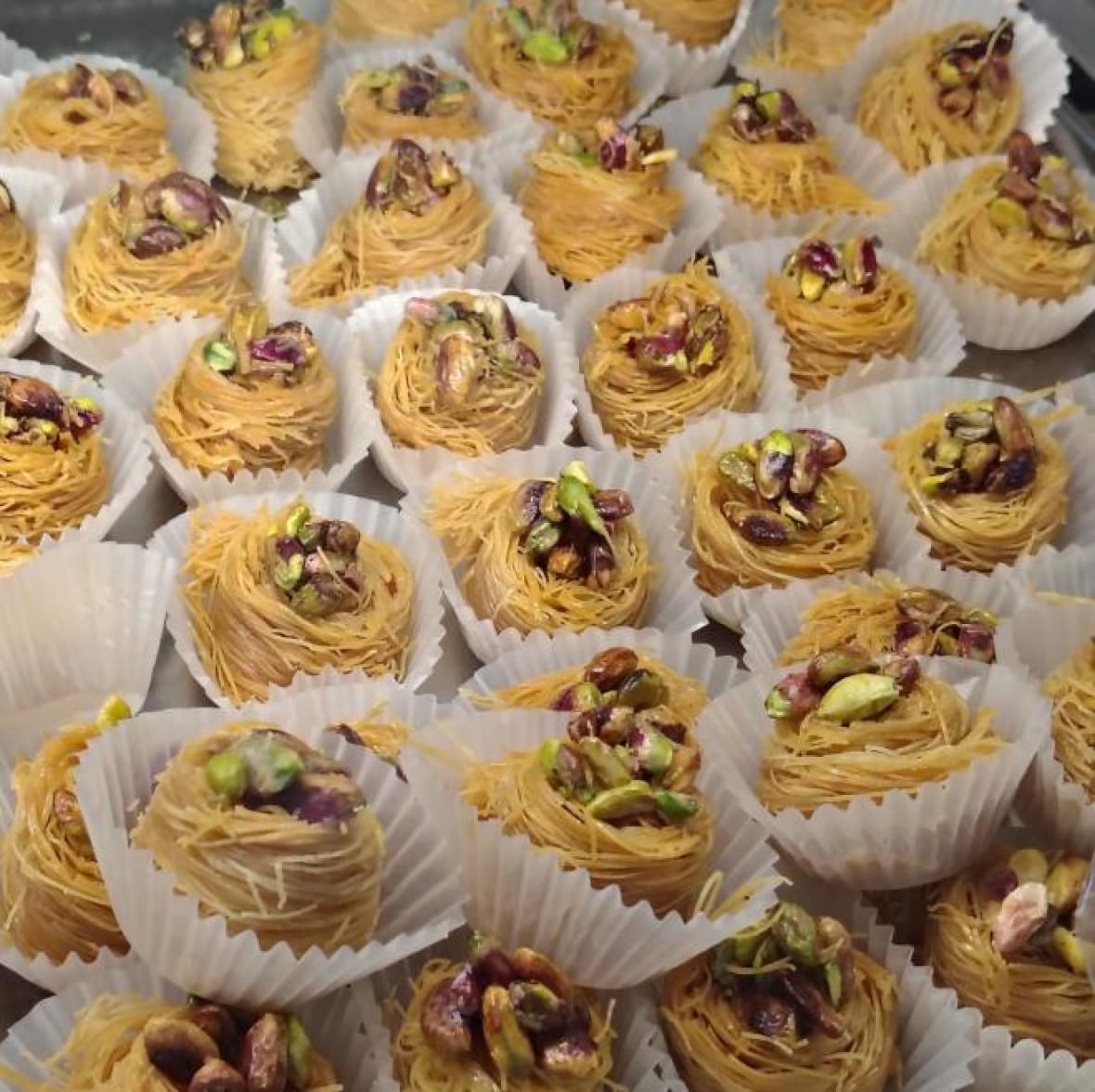 Reihen von Pistazien-Baklava in Muffinförmchen.
