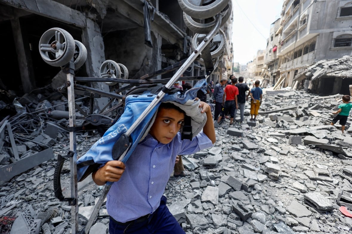 A Palestinian boy carries a stroller at the site of an airstrike.