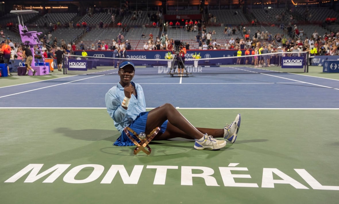 A woman celebrates with a trophy.