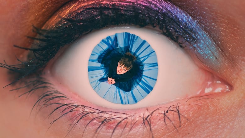 Superimposed on an image of an eyeball, a women sits, wearing a blue skirt, which forms the eye's pupil.