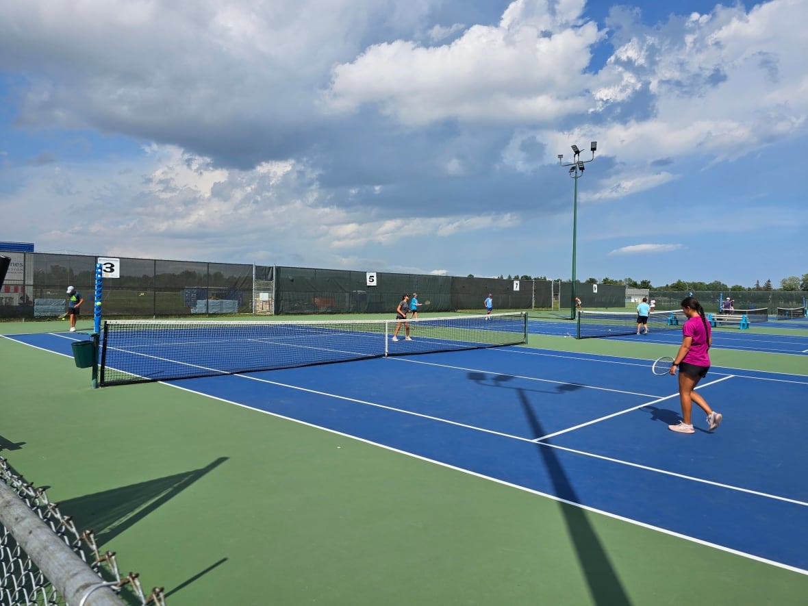 Tennis players on outdoor courts.