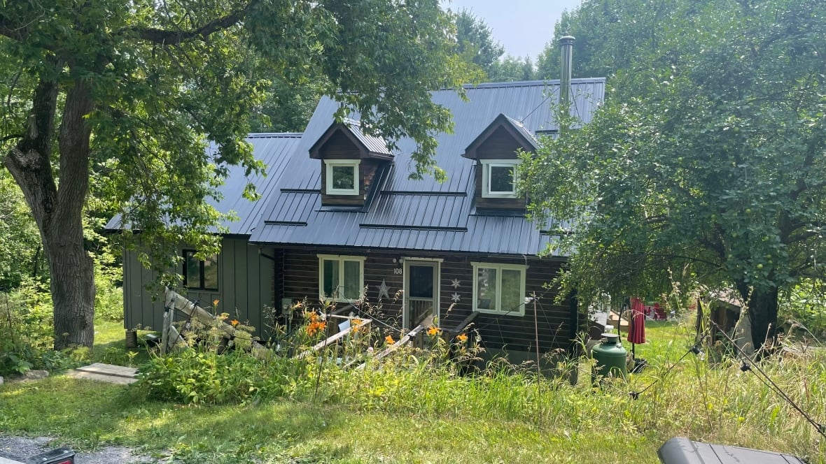 A cottage surrounded by trees and tiger lily blooms.
