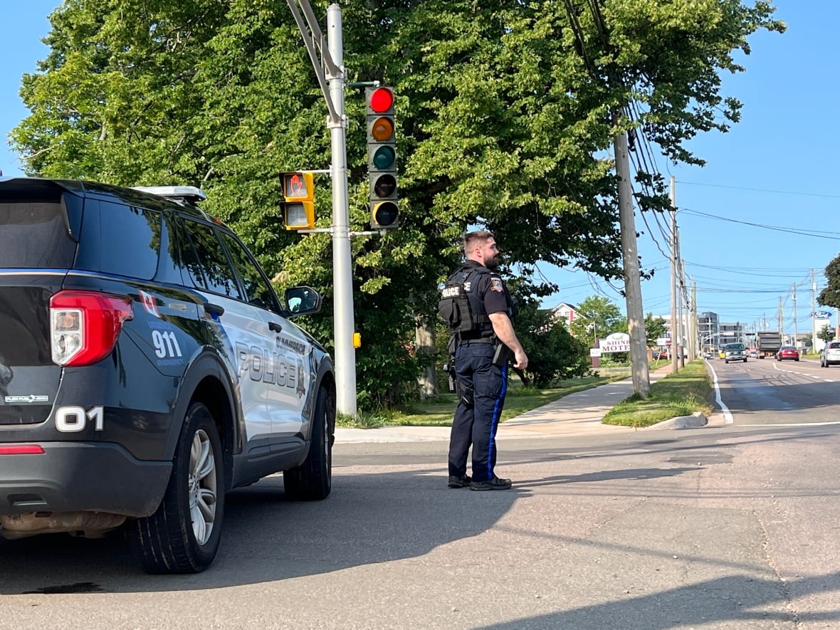 A police officer standing at a roadside next to a police SUV. 