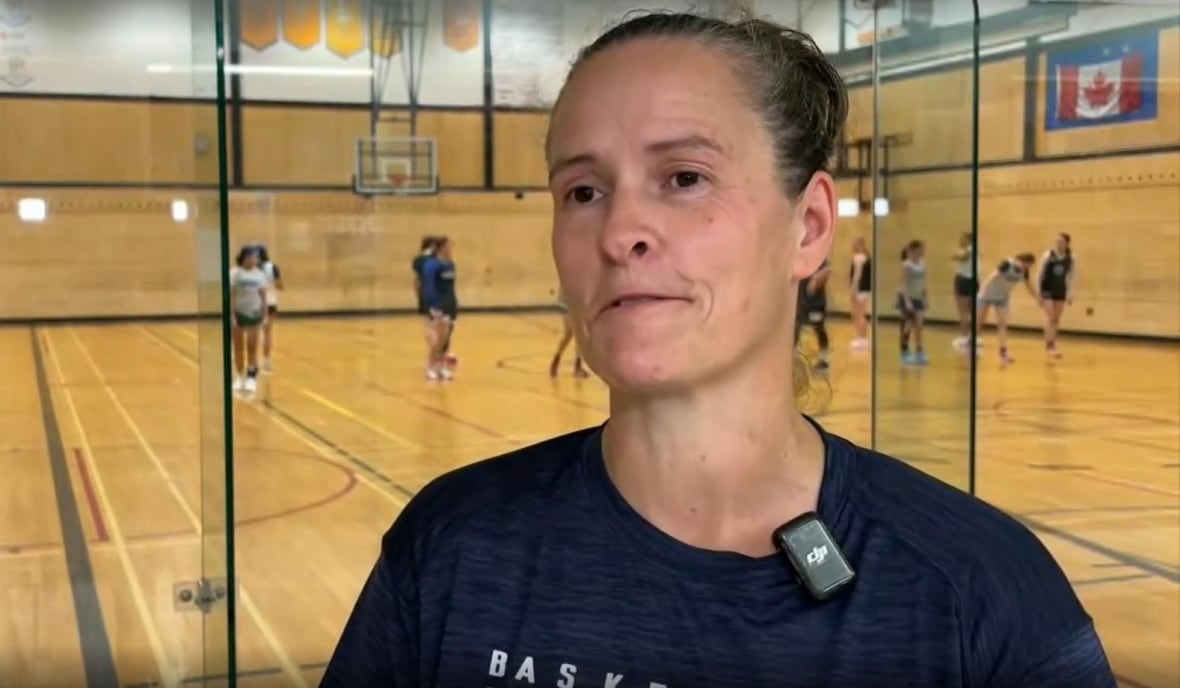 A women standing in front of a basketball players on a court.