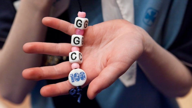 A Girl Guide holds up a "GGC" keychain she made.