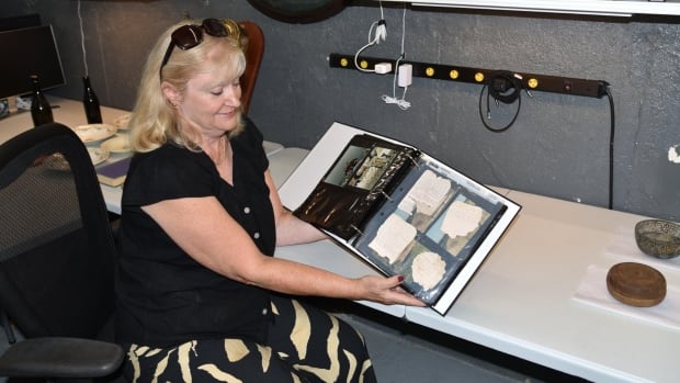 A woman looks through a photo album filled with scraps of paper