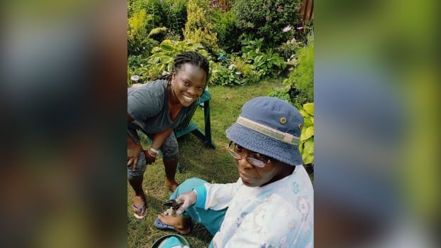 Two women in a garden look up at the camera