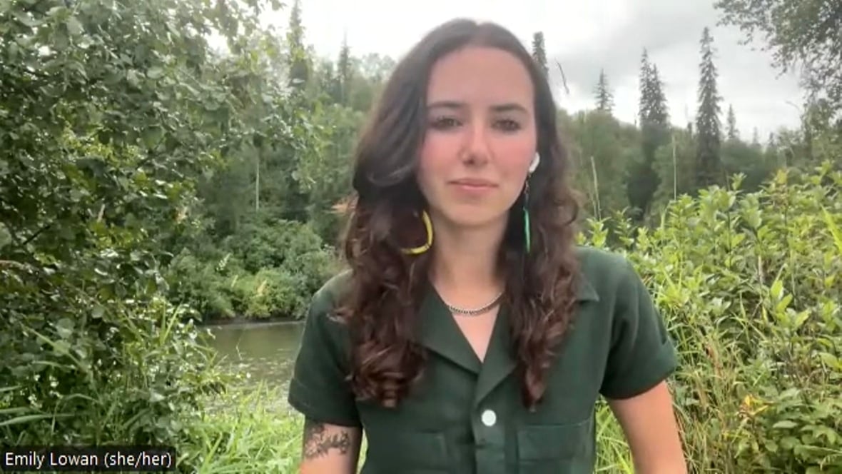 Una mujer con una camisa verde está fuera del área del bosque.