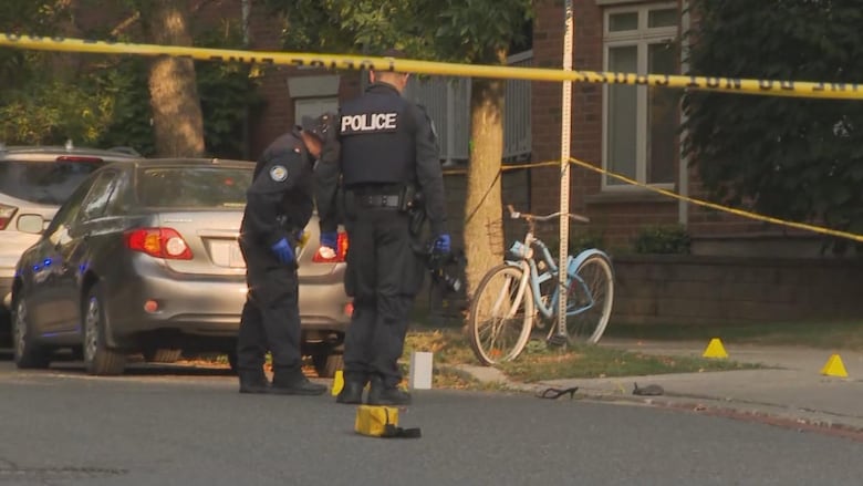 Police look at evidence on the side walk. A heel can be seen on the concrete. 