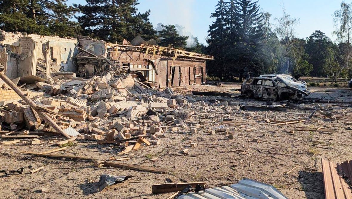 Delivered building is on the left, while some burning cars are visible to the right.