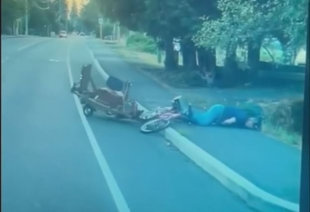 The cyclist can be seen lying on the sidewalk beside the bike and trailer after being knocked into oncoming traffic in this still from the dash cam footage.