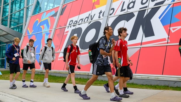 A group of Canada Games athletes walk in front of a building with a large mural that says 'Ready to ROCK.'