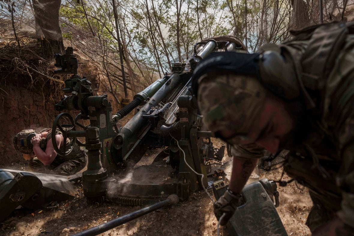 Soldiers take cover after firing a howitzer.