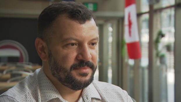 Man wearing a white shirt in front of a Canadian flag in a restaurant