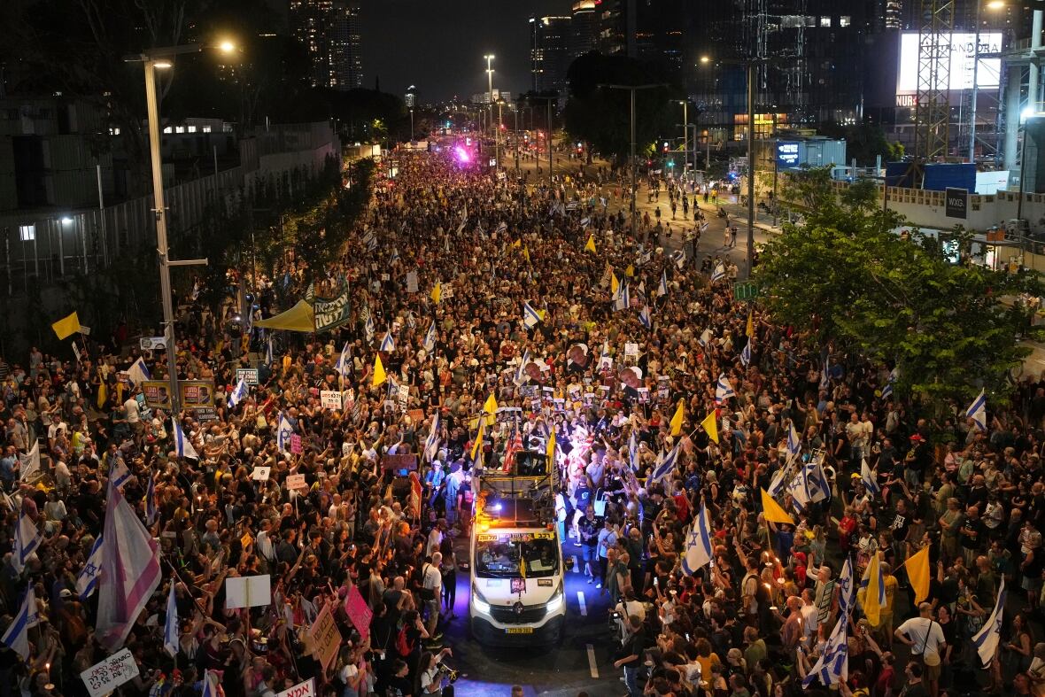 A demonstration at night fills a street several hundred meters back.