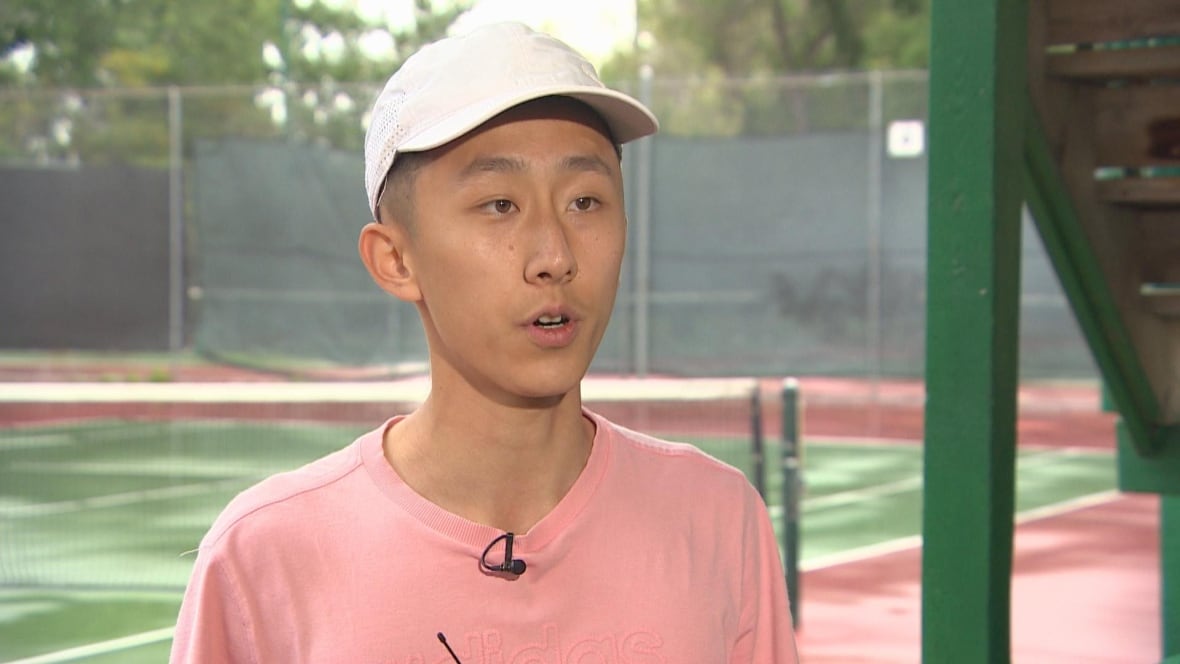 Tennis player speaks in front of a court.