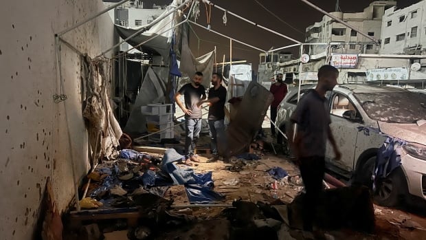 People stand amid debris following an airstrike.