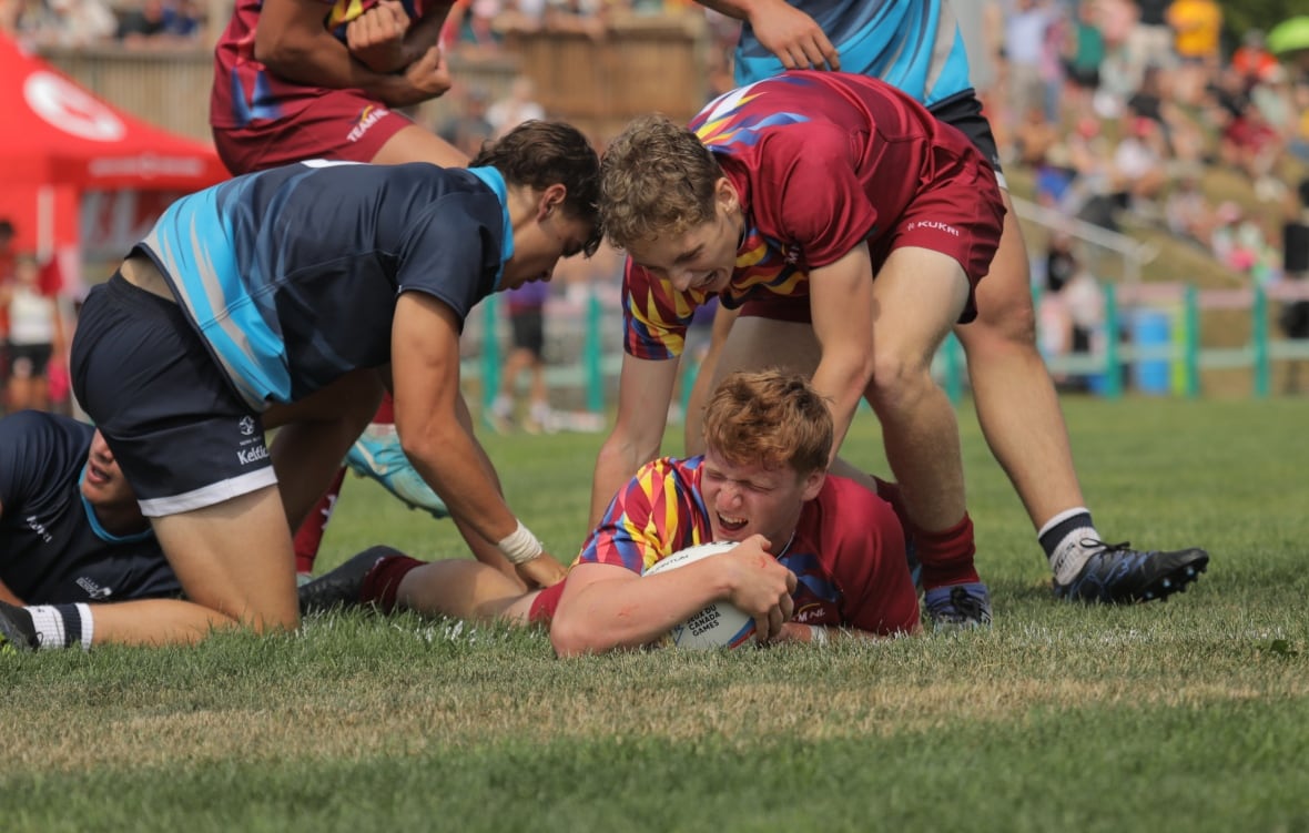 A player on the ground holding the ball and yelling with glee.