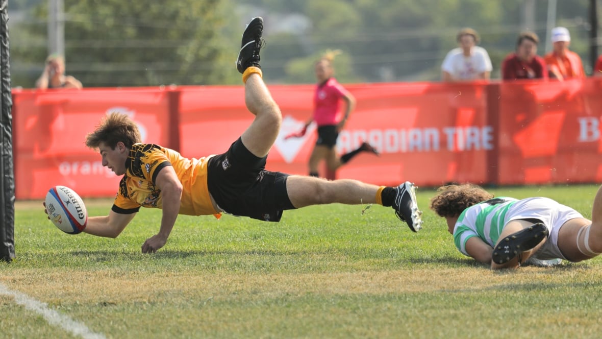 A player diving head first with the ball in an outstretched hand.